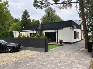 ein schwarzweißes Haus mit einem Auto, das in der Einfahrt parkt in der Unterkunft Széplak No.1. in Siófok