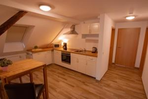 uma cozinha com armários brancos e uma mesa de madeira em Gästehaus Waldeslust em Espenau