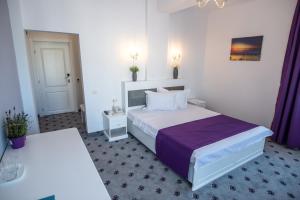 a hotel room with a large bed with purple sheets at Hotel Tadora in Eforie Nord