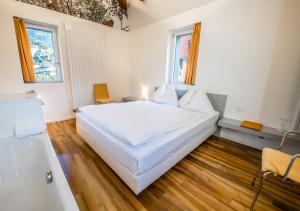 a bedroom with a large white bed and two windows at Hôtel de la Poste Sierre in Sierre