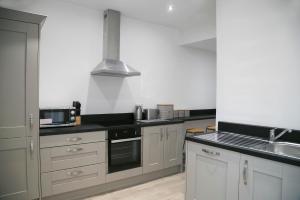 a kitchen with white cabinets and a black counter top at Oswald House deluxe 2 bedroom apartment in Harrogate