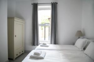 two beds in a room with a window at Oswald House deluxe 2 bedroom apartment in Harrogate