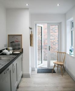 a kitchen with white cabinets and a chair and a window at Oswald House deluxe 2 bedroom apartment in Harrogate