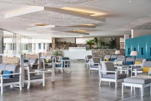 AKS Porto Heli Hotel في بورتوخيلي: مطعم فيه كراسي بيضاء وطاولات ولوبي