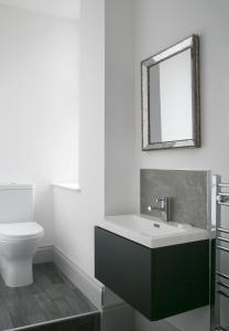 a bathroom with a sink and a toilet and a mirror at Oswald House deluxe 3 bedroom apartment in Harrogate