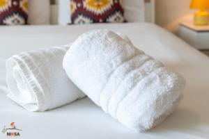 - un rouleau de serviettes blanches assises au-dessus d'un lit dans l'établissement Niksa Serviced Accommodation Welwyn Garden City- One Bedroom, à Welwyn Garden City