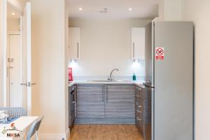 a kitchen with a refrigerator and a table at Niksa Serviced Accommodation Welwyn Garden City- One Bedroom in Welwyn Garden City +10 photos