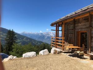 a log cabin with a table and chairs and mountains at CHEZ FOLLO in Mase