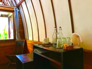 una mesa con botellas encima con una silla en Cotton Tree Cottages en Gili Trawangan