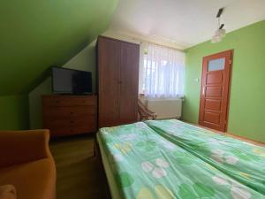 um quarto com uma cama, uma cómoda e uma televisão em Przed Korzeniowym em Kazimierz Dolny