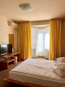 una camera con un grande letto e una televisione di Hotel Victoria a Cluj-Napoca