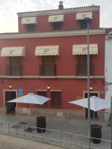 un edificio rojo con dos sombrillas delante en Hostal Pechi en Huévar