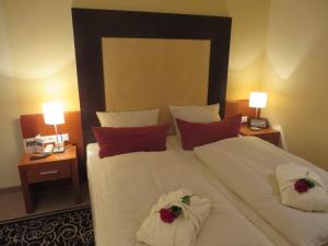 1 dormitorio con 1 cama grande con sábanas blancas y almohadas rojas en Ringhotel Bundschu, en Bad Mergentheim