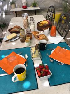 una mesa con alimentos para el desayuno y una taza de café y fresas en B&B Villa de Margot, en Aviñón