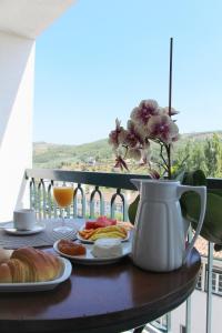 a table with plates of food and a vase of flowers at A Moderna - Guest house Casa dos Serpas in Caldas da Felgueira