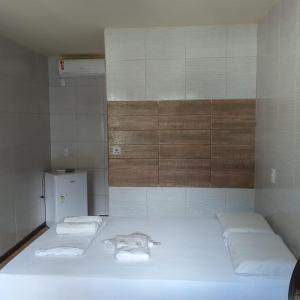 um quarto com uma cama com duas toalhas e um frigorífico em Pousada Preocupacao Zero em Ubajara