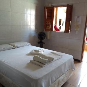 uma cama branca com toalhas por cima em Pousada Preocupacao Zero em Ubajara