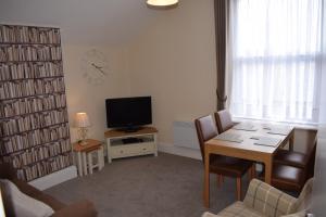 a living room with a television and a table and chairs at Cedar House, formerly Shamrock House in Llandudno