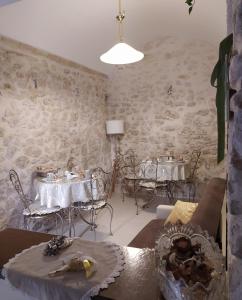 un soggiorno con tavoli, sedie e un muro in pietra di Il viandante a Sulmona