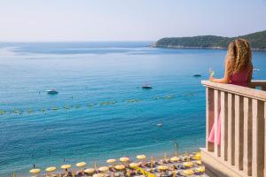 a woman sitting on a balcony looking at the ocean at Poseidon The Beach Hotel in Budva