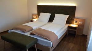 een slaapkamer met 2 bedden en een groene poef bij Kräuterhotel & Restaurant Heidejäger in Mulmshorn
