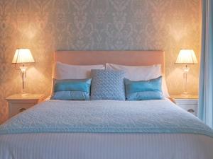 a bedroom with a bed with blue pillows and two lamps at amber house hotel in Paignton