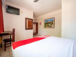 Cette chambre comprend un lit blanc et une télévision murale. dans l'établissement OYO Hotel Betsua Vista Hermosa, Huatulco, à Santa Cruz Huatulco