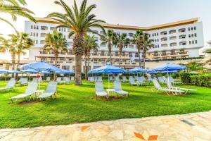 grupa krzeseł i niebieskich parasoli przed hotelem w obiekcie Creta Star Hotel - Adults Only w mieście Skaleta