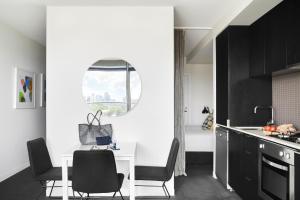 a kitchen with black cabinets and a white table and chairs at Punthill South Yarra Grand in Melbourne