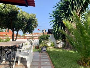 patio ze stołem, krzesłami i drzewami w obiekcie Villa Ana María w mieście Torremolinos