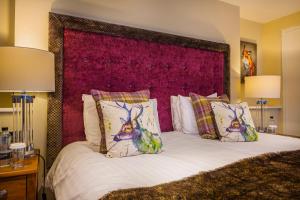 a bedroom with a large bed with a red headboard at The Feathers Hotel, Helmsley, North Yorkshire in Helmsley