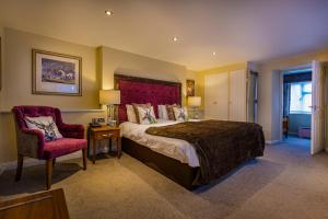 sypialnia z dużym łóżkiem i krzesłem w obiekcie The Feathers Hotel, Helmsley, North Yorkshire w mieście Helmsley