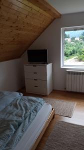 a bedroom with a bed and a television and a window at House of Laura in Băile Tuşnad