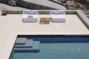 two lounge chairs sitting next to a swimming pool at Bluebird Villas Villa Seabird in Mikonos