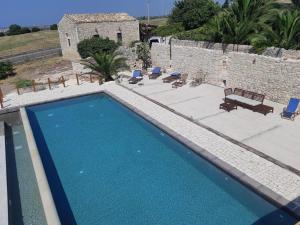 a large swimming pool in front of a stone building at Villa Barone Alfieri in Pozzallo