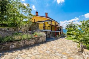 an exterior view of a yellow house with a stone driveway at Rona Apartment & Rooms Mea Vista in Buzet