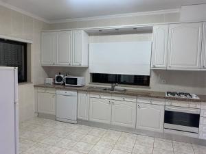 a kitchen with white cabinets and a sink and a window at Douro Nest Houses in Caldas de Aregos