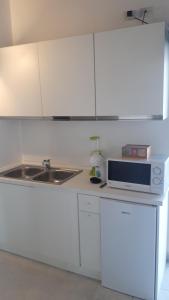 una cucina con armadi bianchi, lavandino e forno a microonde di casa leonardo ad Azzano San Paolo