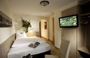 a hotel room with a bed and a flat screen tv at HartlWirt Gasthof-Hotel in Salzburg