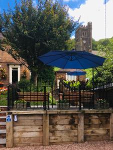 une table avec un parapluie bleu et quelques bancs dans l'établissement Foundry Masters House, à Ironbridge