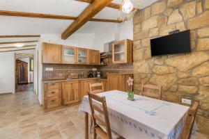 a kitchen with a table and a tv on a stone wall at Rona Apartment & Rooms Mea Vista in Buzet