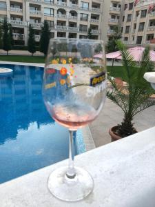 a wine glass sitting on a table next to a pool at East from Paradise Apartment in Varna City