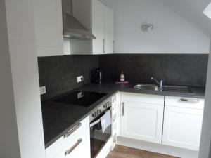 a kitchen with white cabinets and a black counter top at Schinderhanneshof in Weitersborn