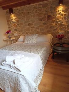 1 dormitorio con cama blanca y pared de piedra en Casa Rural La Bodega, en Aldeadávila de la Ribera