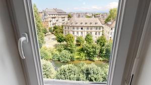 a window with a view of a river and buildings at Le Quai KOCH in Strasbourg