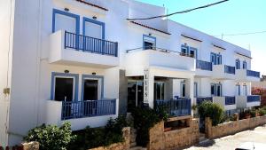 a white house with blue balconies on a street at Luis Apartments in Mastihari