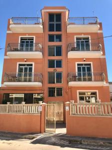 wysoki pomarańczowy budynek z balkonem w obiekcie Hotel Ristorante Scirocco w mieście Portopalo