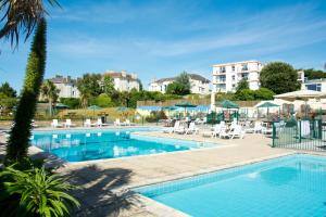 uma piscina com cadeiras e um hotel em TLH Victoria Hotel - TLH Leisure, Entertainment and Spa Resort em Torquay