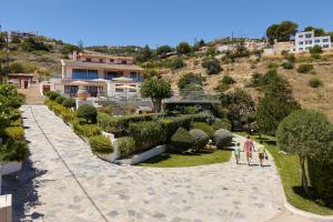 Ein Mann und zwei Kinder gehen durch einen Garten in der Unterkunft Keramos Villa & Apartments in Agia Pelagia