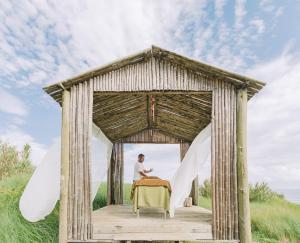 a man sitting at a table in a gazebo at Santa Barbara Eco-Beach Resort in Ribeira Grande